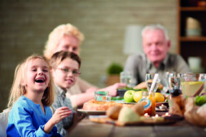 Ein älteres Paar sitzt gemeinsam mit ihren Enkelkindern zum essen am Tisch. Mangelernährung stellt für die beiden kein Problem mehr dar.