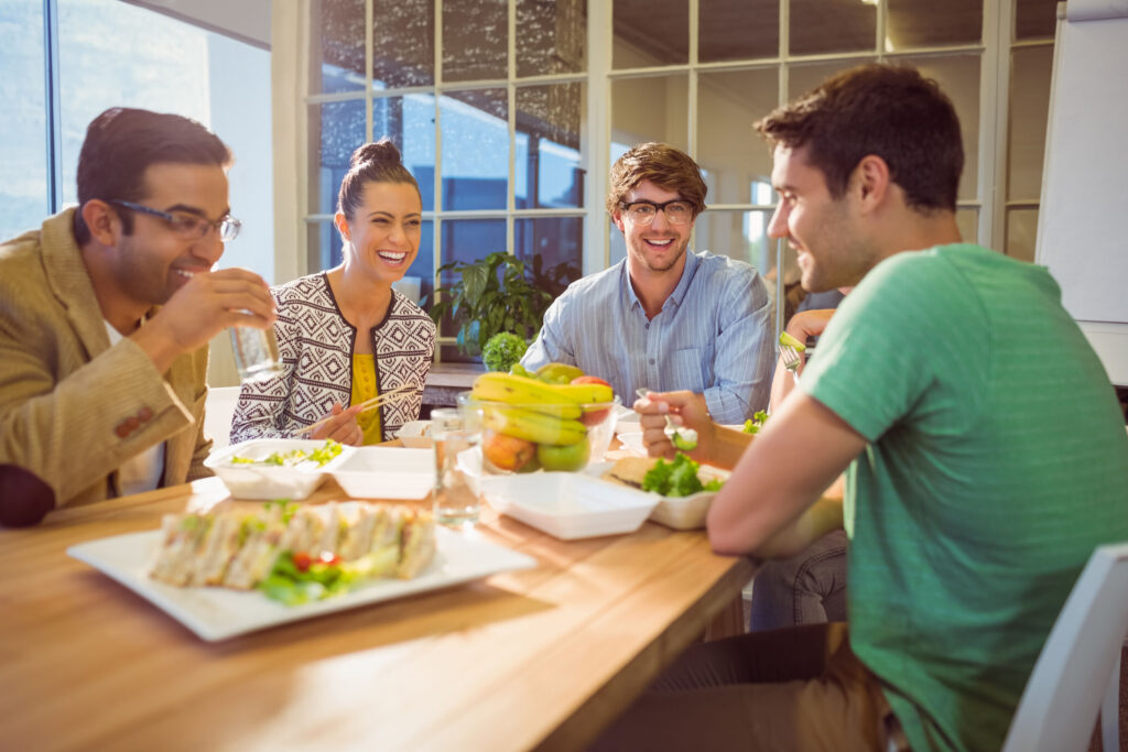 Vor dem Powernap: eine Gruppe von Arbeitnehmern sitzen gemeinsam an einem Tisch und essen.