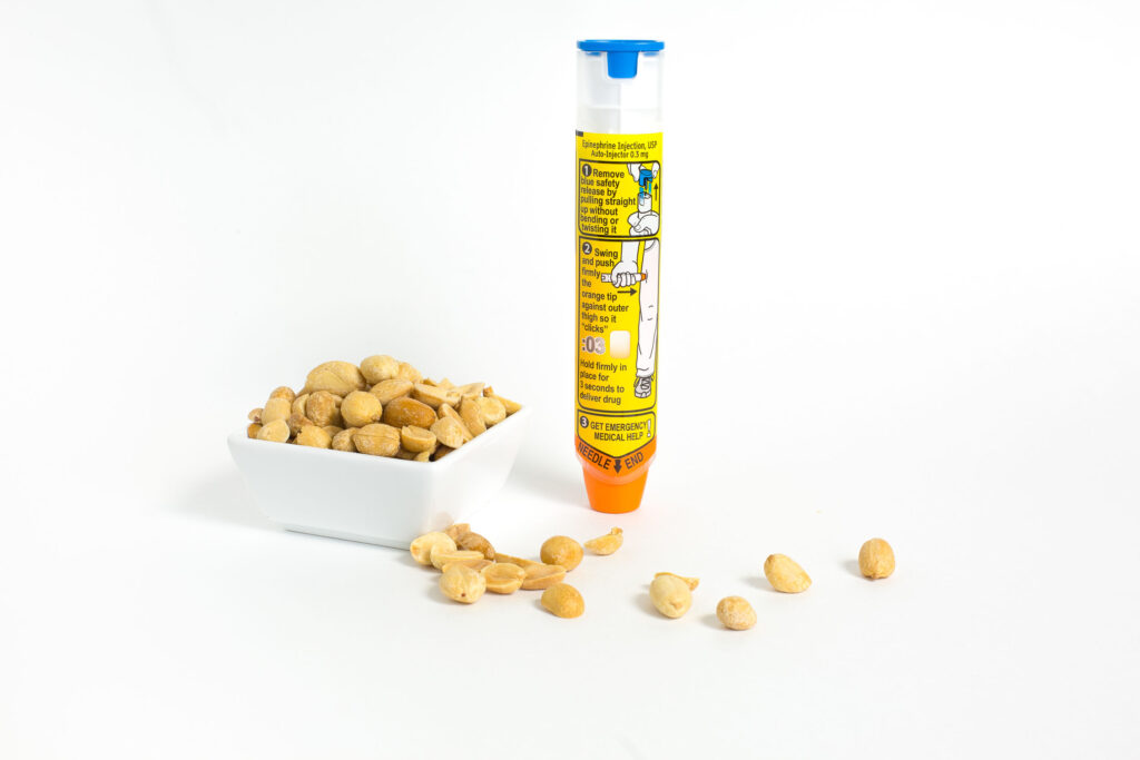 Ein Epi-Pen für Allergien steht neben einer Schale von Erdnüssen